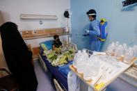 A child who suffers from cancer sits on a bed as a worker sprays disinfectant at the Children's Hospital for Cancer Diseases in Basra