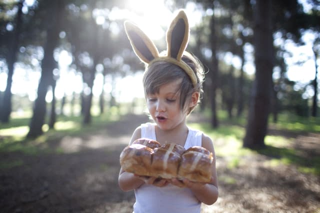Boy in forest  bunny ears with hot cross buns