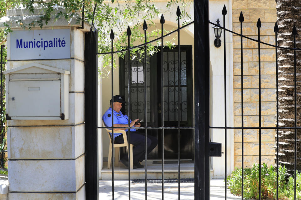 A security man sits at the closed main entrance of a municipality which is under an open strike, in Bramiyeh, south Lebanon, July 27, 2022. Tens of thousands of Lebanese public sector workers are on strike for a sixth week as they struggle to cope with the country's crippling economic crisis. (AP Photo/Mohammed Zaatari)