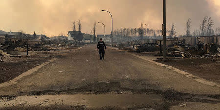 FILE PHOTO -- A Mountie surveys the damage on a street in Fort McMurray, Alberta, Canada in this May 4, 2016 image posted on social media. Courtesy Alberta RCMP/Handout via REUTERS