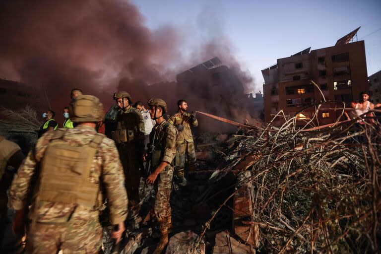 Soldados del ejército libanés y personas se reúnen en el lugar de los ataques aéreos israelíes en el barrio de Haret Hreik, en los suburbios del sur de Beirut, el 27 de septiembre de 2024.