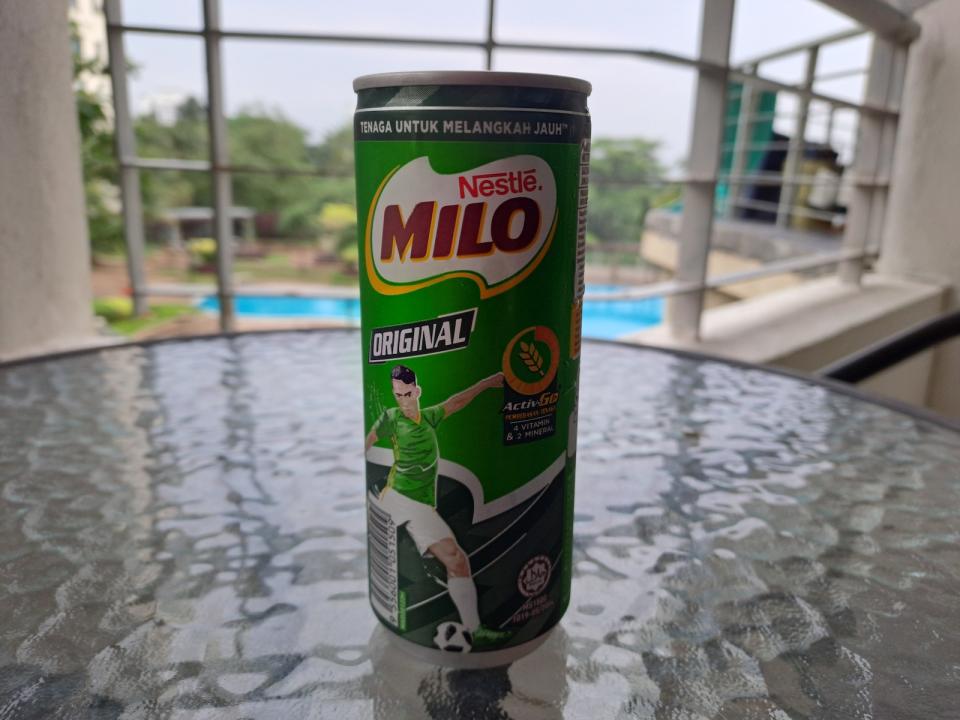 A can of the chocolate malt drink, Milo, on a glass table.