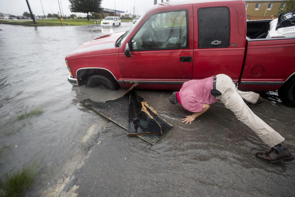 Felipe Morales works on getting his truck out of a ditch filled with high water during a rain storm stemming from rain bands spawned by Tropical Storm Imelda on Tuesday, Sept. 17, 2019, in Houston. He was able to get help when a man with a truck helped pull him from the ditch. (Brett Coomer/Houston Chronicle via AP)