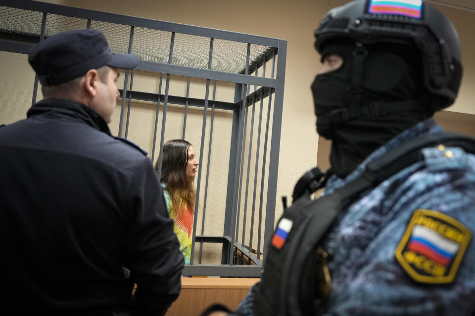 Sasha Skochilenko, a 33 year-old artist and musician reacts standing behind bars in the court room in the Vasileostrovsky district court in St. Petersburg, Russia, Thursday, Nov. 16, 2023. Skochilenko has been convicted of spreading false information about the military and sentenced to 7 years in prison after replacing several supermarket price tags with slogans criticizing Russia's military action in Ukraine. (AP Photo/Dmitri Lovetsky)