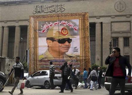 People walk past a huge banner for Egypt's army chief, Field Marshal Abdel Fattah al-Sisi in front of the High Court of Justice in downtown Cairo in this March 13, 2014 file photo. REUTERS/Amr Abdallah Dalsh/Files