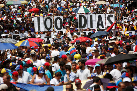 Opposition supporters hold letters to build a banner that reads "100 days" during a rally against Venezuelan President Nicolas Maduro's government in Caracas. REUTERS/Carlos Garcia Rawlins