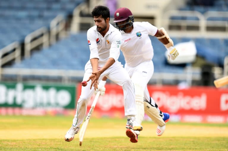 Pakistan's bowler Mohammad Amir (L) stops the ball as West Indies' batsman Shannon Gabriel takes a run on April 23, 2017