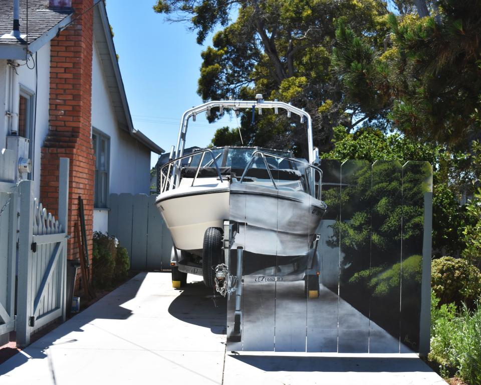 The opposite half of Etienne Constable's boat is visible from behind a hyper-realistic mural, painted by next-door neighbor Hanif Panni. The two men decided to make the mural to comply with a city rule in a creative way.