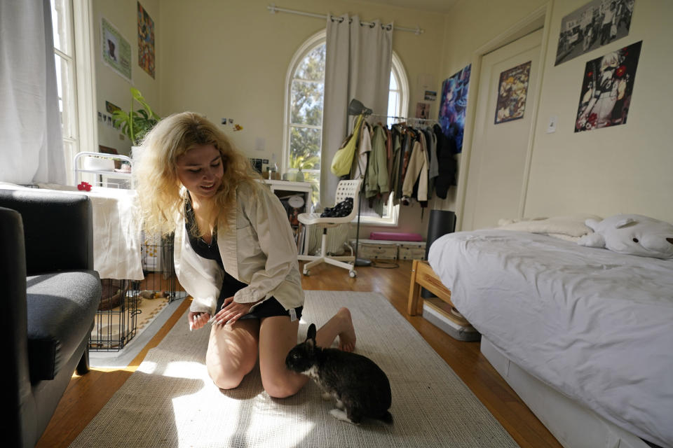 University of California, Berkeley junior Sofia Howard-Jimenez, plays with her rabbit in her converted dining room bedroom of the apartment she shares with three others in Berkeley, Calif., Tuesday, March 29, 2022. Millions of college students in the U.S. are trying to find an affordable place to live as rents surge nationally, affecting seniors, young families and students alike. (AP Photo/Eric Risberg)