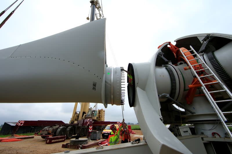 FILE PHOTO: Employees work on a rotor blade assembling to the hub of an E-70 wind turbine manufactured by German company Enercon for La Compagnie du Vent during its installation at a wind farm in Meneslies, Picardie region