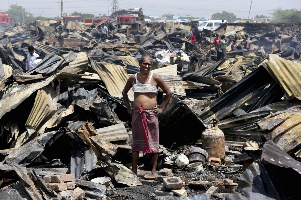 An Indian man stands at the site of his home as he watches the devastation around him after a fire in a shanty town in New Delhi, India, Friday, April 25, 2014. A massive fire ripped through a New Delhi slum Friday, destroying nearly 500 thatched huts and leaving already impoverished families homeless, said a fire department official. Seven people were hospitalized with minor burn wounds. (AP Photo/Manish Swarup)