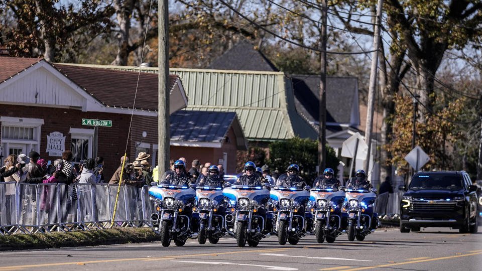 People watch the motorcade as it moves to Maranatha Baptist Church where the funeral service for former first lady Rosalynn Carter will be held, Wednesday, Nov. 29, 2023, in Plains, Ga. The former first lady died on Nov. 19. She was 96. (AP Photo/Brynn Anderson)