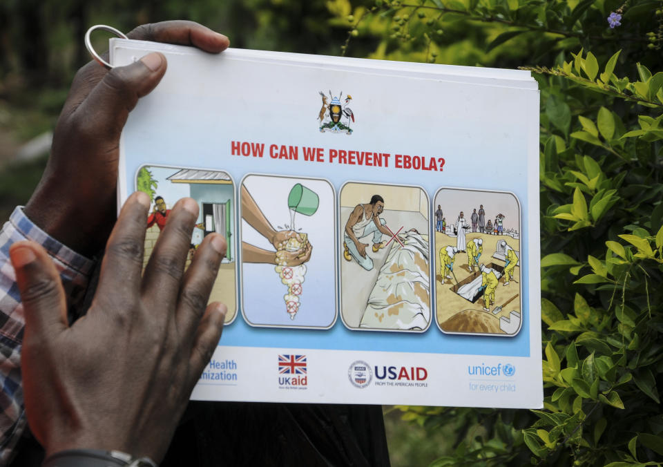 A health worker educates relatives of the 5-year-old boy who became Ebola's first cross-border victim, and other villagers, about Ebola symptoms and prevention, in the village of Kirembo, near the border with Congo, in western Uganda Saturday, June 15, 2019. The World Health Organization (WHO) in Uganda said Saturday that it has started ring vaccination of all contacts of the confirmed Ebola cases including health workers. (AP Photo/Ronald Kabuubi)