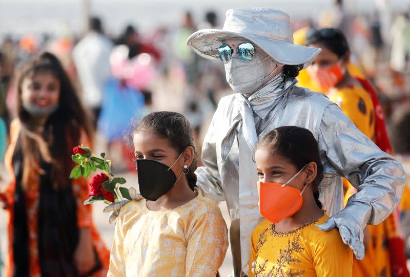 People pose with a performance artist at a beach amidst the spread of the coronavirus disease (COVID-19) in Mumbai