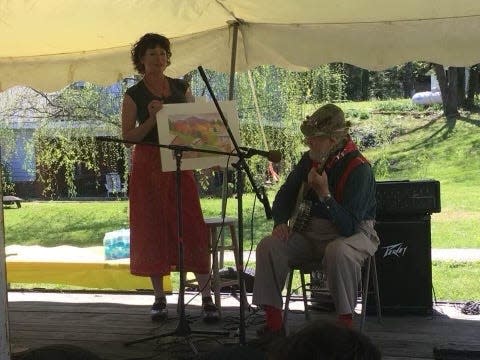 Kate Hubbard is joined by Peter Gott on stage to promote a silent auction item, a watercolor by Polly Gott, at Trailfest.