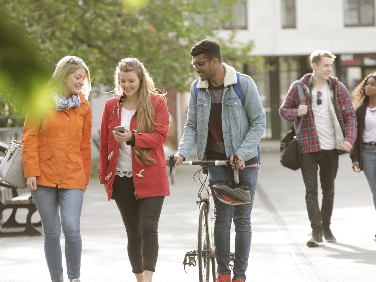 College students looking at a phone and walking on campus