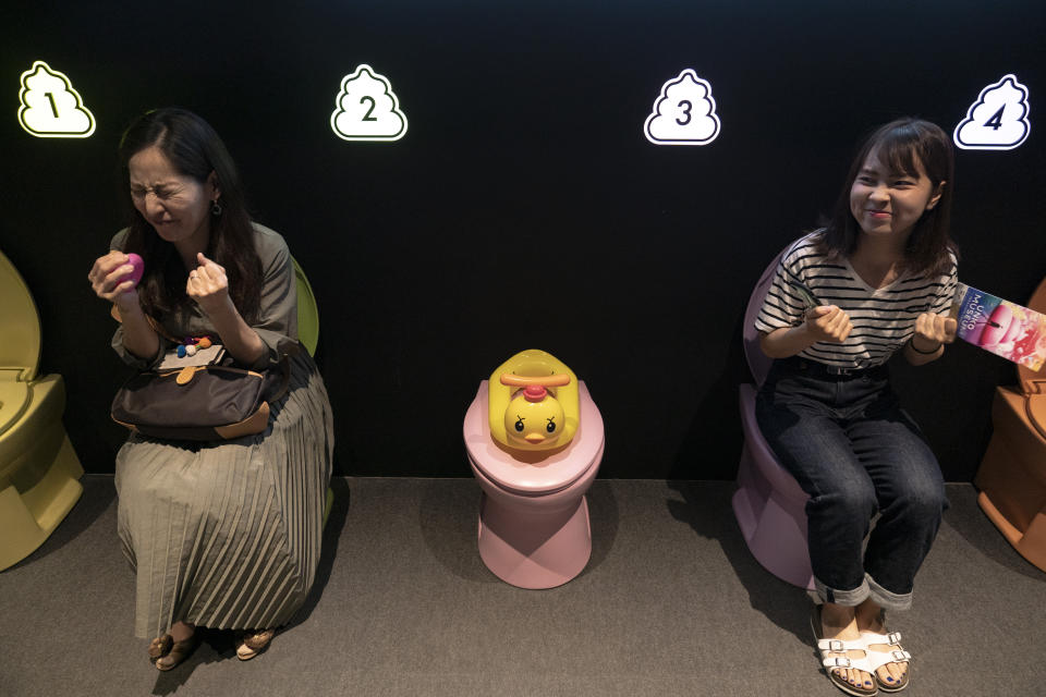 In this Tuesday, June 18, 2019, photo, two women jokingly motion to give a push while sitting on colorful toilet bowls at the Unko Museum in Yokohama, south of Tokyo. In a country known for its cult of cute, even poop is not an exception. A pop-up exhibition at the Unko Museum in the port city of Yokohama is all about unko, a Japanese word for poop. The poop installations there get their cutest makeovers. They come in the shape of soft cream, or cupcake toppings. (AP Photo/Jae C. Hong)