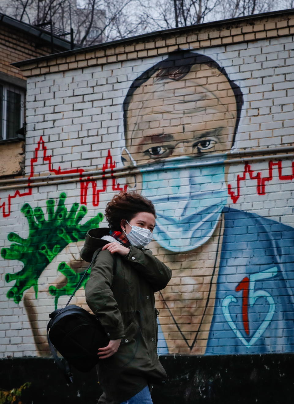 A woman walks past a mural of a doctor fighting coronavirus in Russia.