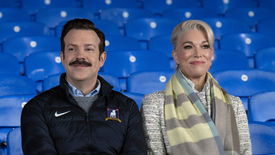 (L, R) Jason Sudeikis as Ted Lasso and Hannah Waddingham as Rebecca Waddingham sit together in the Richmond stands in Ted Lasso season 3 episode 12, 