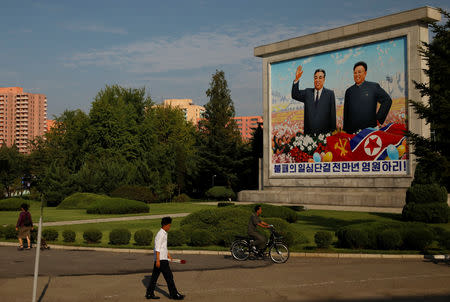 Residents pass by a painting featuring late North Korean leaders Kim Il-sung (L) and Kim Jong-il ahead of 70th anniversary of North Korea's foundation in Pyongyang, September 6, 2018. REUTERS/Danish Siddiqui