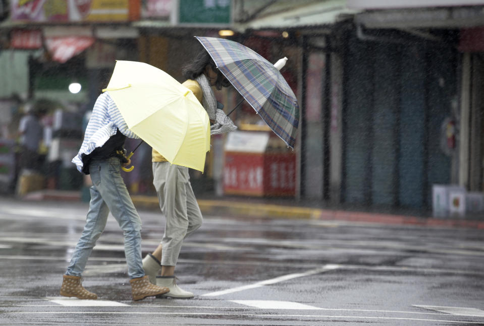 Two Taiwanese women make their way against powerful gusts of wind generated by typhoon Lekima in Taipei, Taiwan, Friday, Aug. 9, 2019. (AP Photo/Chiang Ying-ying)