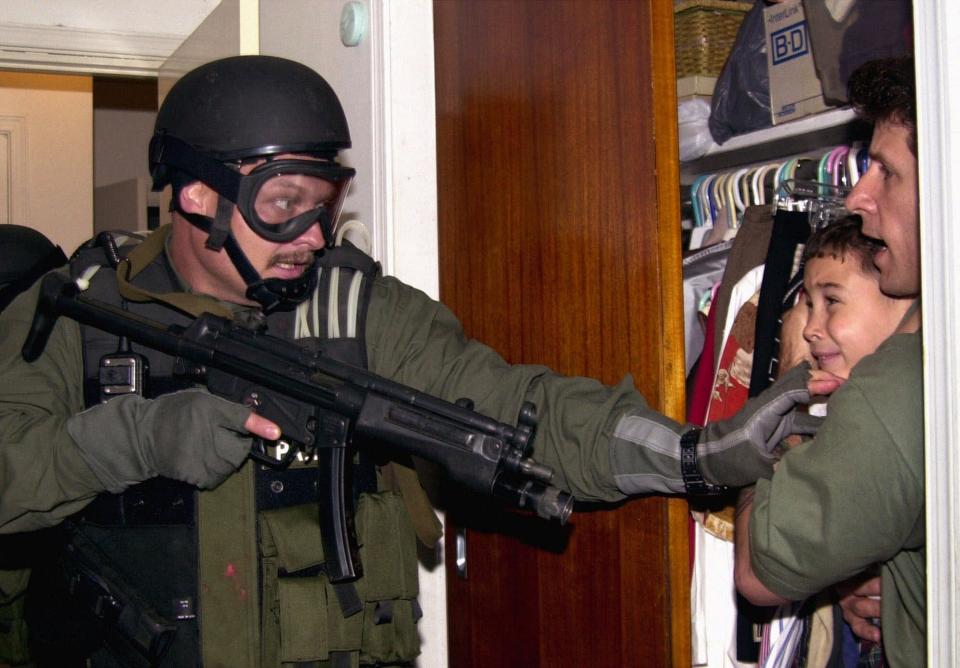 Elian Gonzalez is held in a closet by Donato Dalrymple, right, as government officials search the home of Lazaro Gonzalez for the young boy, early Saturday morning in Miami, April 22, 2000.