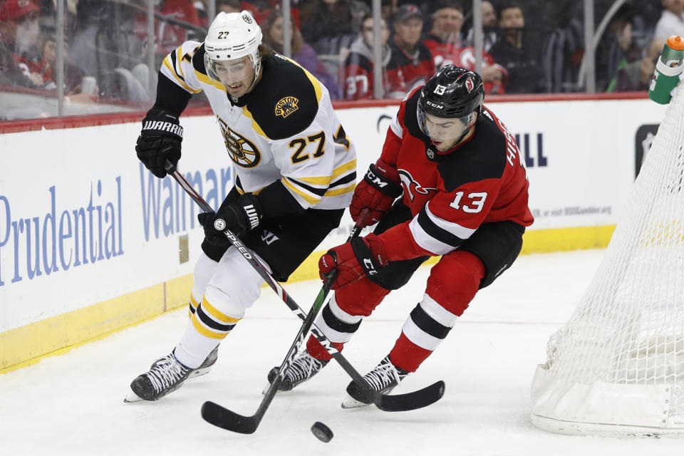 New Jersey Devils center Nico Hischier (13) battles for the puck with Boston Bruins defenseman John Moore (27) during the second period of an NHL hockey game, Tuesday, Dec. 31, 2019, in Newark, N.J. (AP Photo/Kathy Willens)