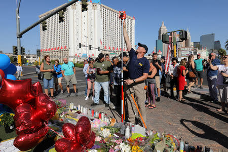 A member of the FBI Evidence Response Team works to map the crime scene near a memorial in the middle of Las Vegas Boulevard following the mass shooting in Las Vegas, Nevada, U.S., October 4, 2017. REUTERS/Mike Blake