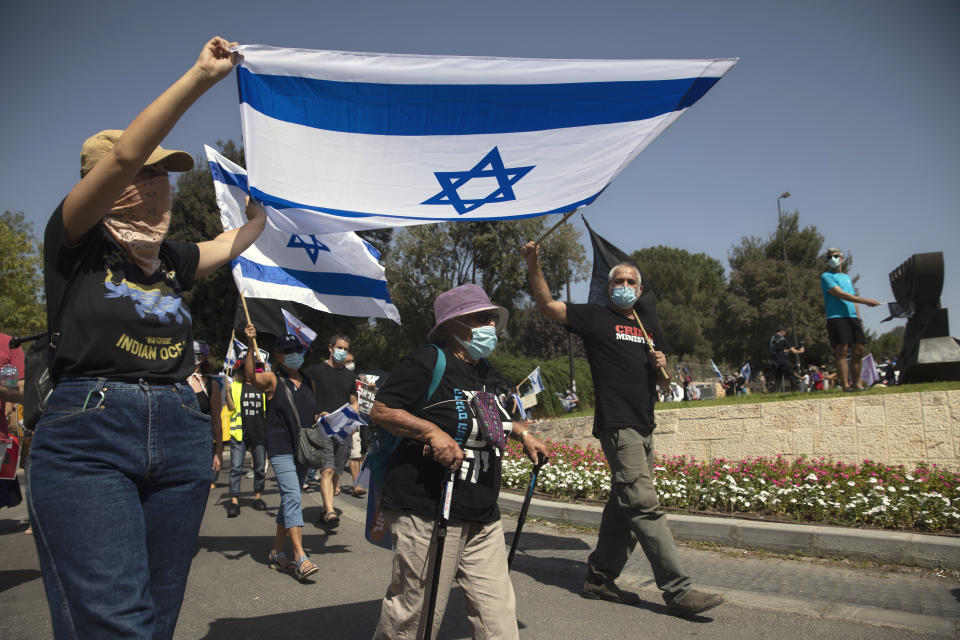 Israeli protesters wave flags and chant slogans during a demonstration against a proposed measure to curtail public demonstrations during the current nationwide lockdown due to the coronavirus pandemic, in front of the Knesset, Israel's parliament in Jerusalem, Tuesday, Sept. 29, 2020. (AP Photo/Sebastian Scheiner)