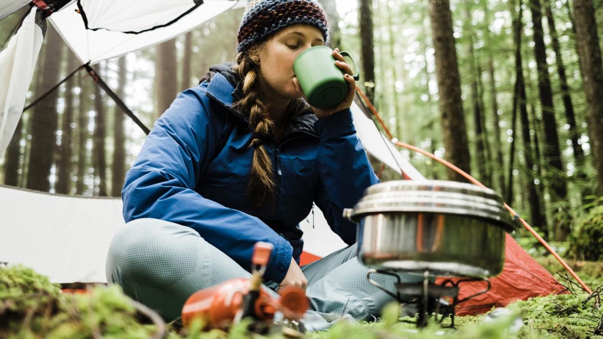  Woman camping and using stove. 