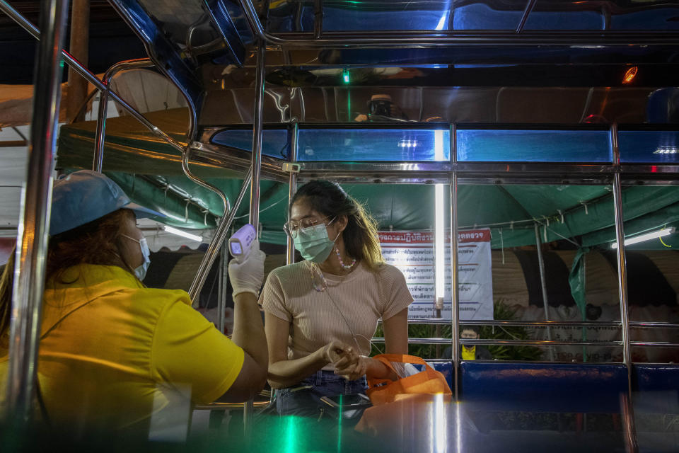 A worker checks body temperature of a passenger of a vehicle at a roadside check point in the border of Samut Sakhon province and Bangkok in Thailand, Monday, Jan. 4, 2021. For much of 2020, Thailand had the coronavirus under control. After a strict nationwide lockdown in April and May, the number of new local infections dropped to zero, where they remained for the next six months. However, a new outbreak discovered in mid-December threatens to put Thailand back where it was in the toughest days of early 2020. (AP Photo/Gemunu Amarasinghe)