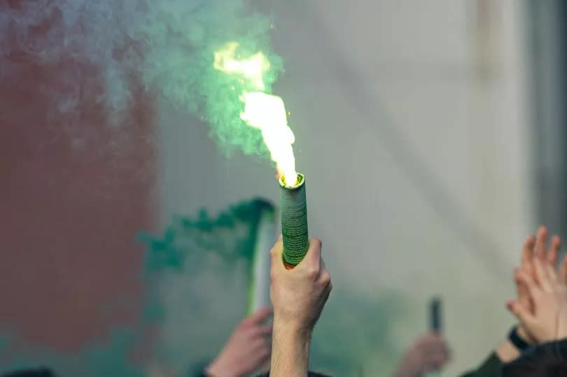 Celtic fans light up the air in green and white as they wave flares outside the stadium.