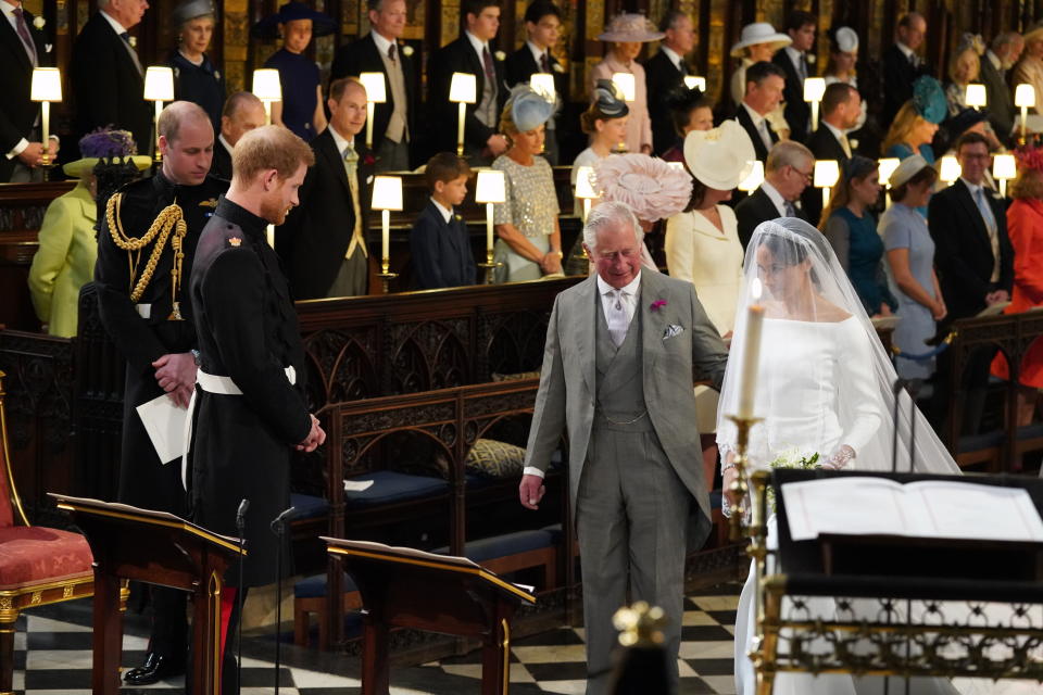 TOPSHOT - Britain's Prince Harry, Duke of Sussex (2nd L), looks at his bride, Meghan Markle, as she arrives accompanied by the Britain's Prince Charles, Prince of Wales in St George's Chapel during the wedding ceremony of Britain's Prince Harry, Duke of Sussex and US actress Meghan Markle in St George's Chapel, Windsor Castle, in Windsor, on May 19, 2018. (Photo by Jonathan Brady / POOL / AFP)        (Photo credit should read JONATHAN BRADY/AFP via Getty Images)