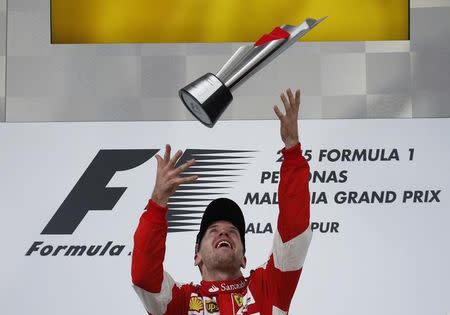 Formula One - F1 - Malaysian Grand Prix 2015 - Sepang International Circuit, Kuala Lumpur, Malaysia - 29/3/15 Ferrari's Sebastian Vettel throws the trophy into the air as he celebrates winning the Malaysian Grand Prix on the podium Reuters / Olivia Harris Livepic