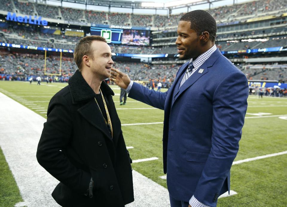 Actor Aaron Paul, left, talks to former NFL football player Michael Strahan before the NFL Super Bowl XLVIII football game between the Seattle Seahawks and the Denver Broncos, Sunday, Feb. 2, 2014, in East Rutherford, N.J. (AP Photo/Evan Vucci)