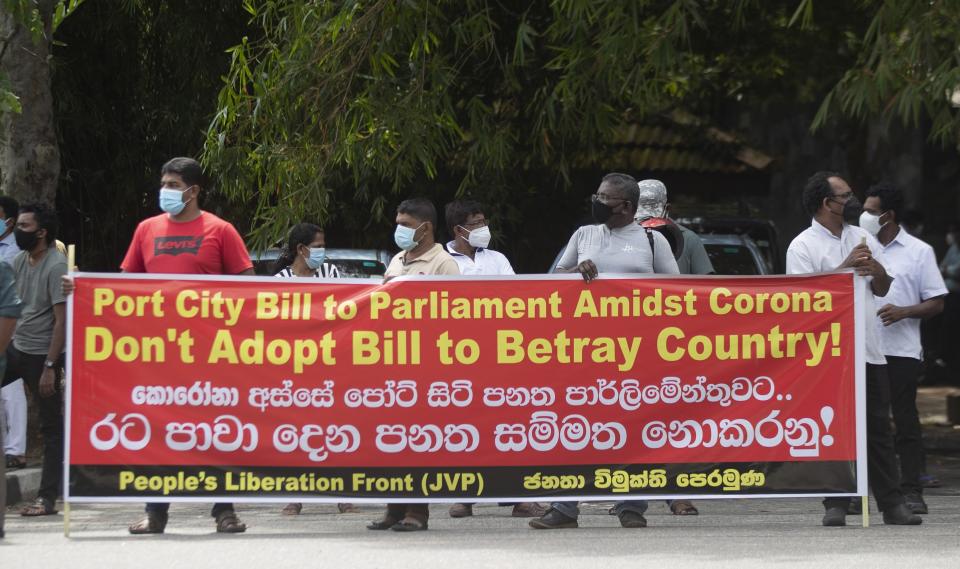 Nearly two dozen protestors belonging to the People's Liberation Front display a banner against the Chinese built port city project in Colombo, Sri Lanka, Wednesday, May 19, 2021. Sri Lanka's top court has ruled that some provisions of legislation to set up a powerful economic commission in a Chinese-built port city violate the constitution and require approval by a public referendum to become law. (AP Photo/Eranga Jayawardena)