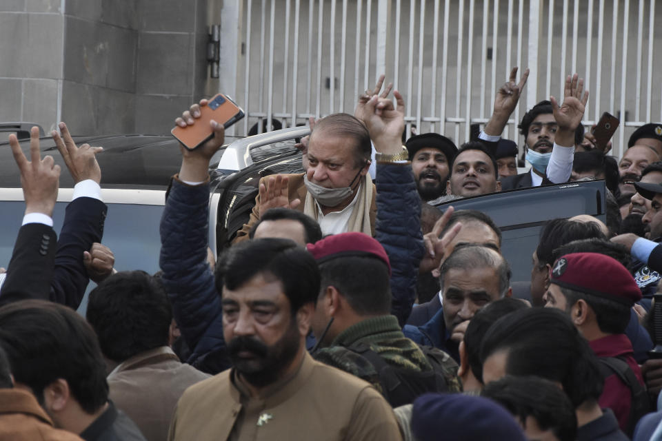 Pakistan's former Prime Minister Nawaz Sharif, center in brown coat, waves to his supporters as he leaves after a court hearing in Islamabad, Pakistan, Tuesday, Dec. 12, 2023. A Pakistani court on Tuesday overturned the 2018 conviction of former Prime Minister Sharif in a graft case and acquitted him, clearing his path to run in the parliamentary elections set to be held in February. (AP Photo/W.K. Yousufzai)