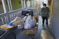 Evelyn Maysonet looks at the food delivery from the Weber-Morgan Health Department Tuesday, Nov. 24, 2020, in Ogden, Utah. Maysonet has been isolating with her husband and son in their Ogden home since all three tested positive for COVID-19 over a week ago. None of them have been able to leave home to buy groceries so Maysonet said they were thrilled to receive the health department's delivery. (AP Photo/Rick Bowmer)