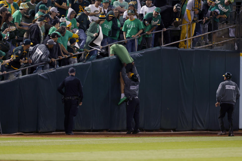 A security worker keeps a person who had run onto the field from climbing back into the stands during the eighth inning of a baseball game between the Oakland Athletics and the Tampa Bay Rays in Oakland, Calif., Tuesday, June 13, 2023. (AP Photo/Jed Jacobsohn)