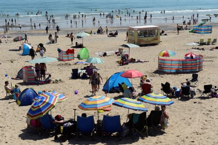 Holidaymakers shelter under umbrellas on the South Beach,Tenby, Pembrokeshire, Wales