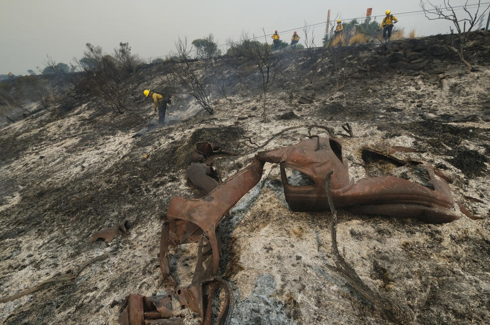 County of Santa Barbara Fire Department firefighters extinguish a roadside fire next to train tracks off of the U.S. 101 highway Wednesday, Oct. 13, 2021, in Goleta, Calif. A wildfire raging through Southern California coastal mountains threatened ranches and rural homes and kept a major highway shut down Wednesday as the fire-scarred state faced a new round of dry winds that raise risk of flames. The Alisal Fire covered more than 22 square miles (57 square kilometers) in the Santa Ynez Mountains west of Santa Barbara. (AP Photo/Ringo H.W. Chiu)