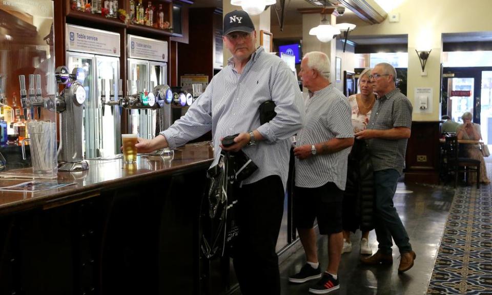 Middle-aged adults in a Manchester pub wait at the bar to be served last week after the lifting of Covid restrictions.