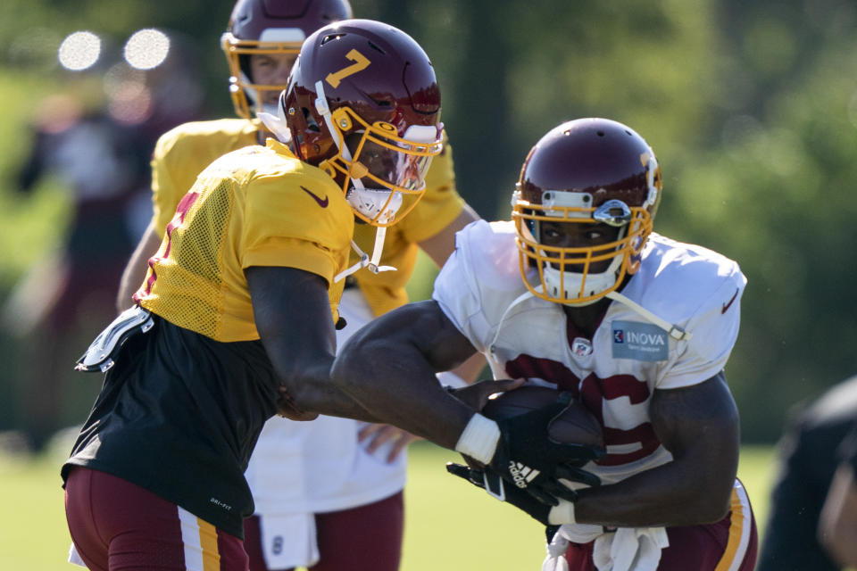 Washington quarterback Dwayne Haskins Jr. (7) hands the ball off to running back Adrian Peterson (26) during practice at the team's NFL football training facility, Tuesday, Aug. 18, 2020, in Ashburn, Va. (AP Photo/Alex Brandon)