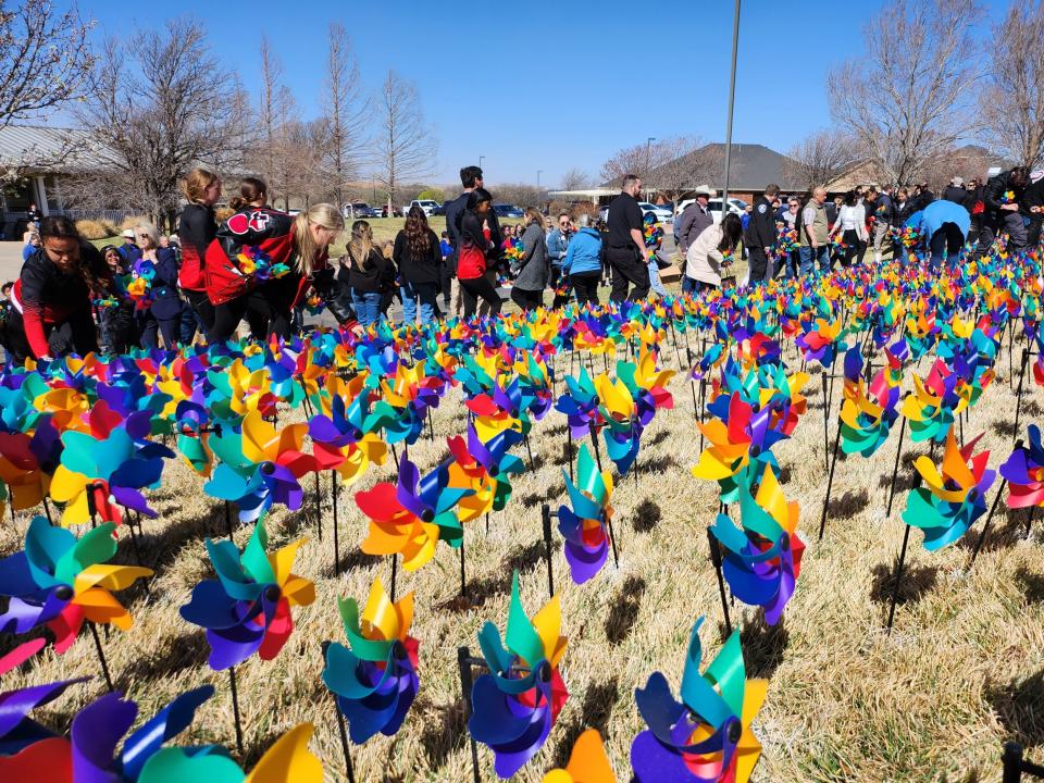 Community members plant 1,335 pinwheels on The Bridge lawn Friday afternoon in honor of every child served in 2022 and Child Abuse Prevention Month.