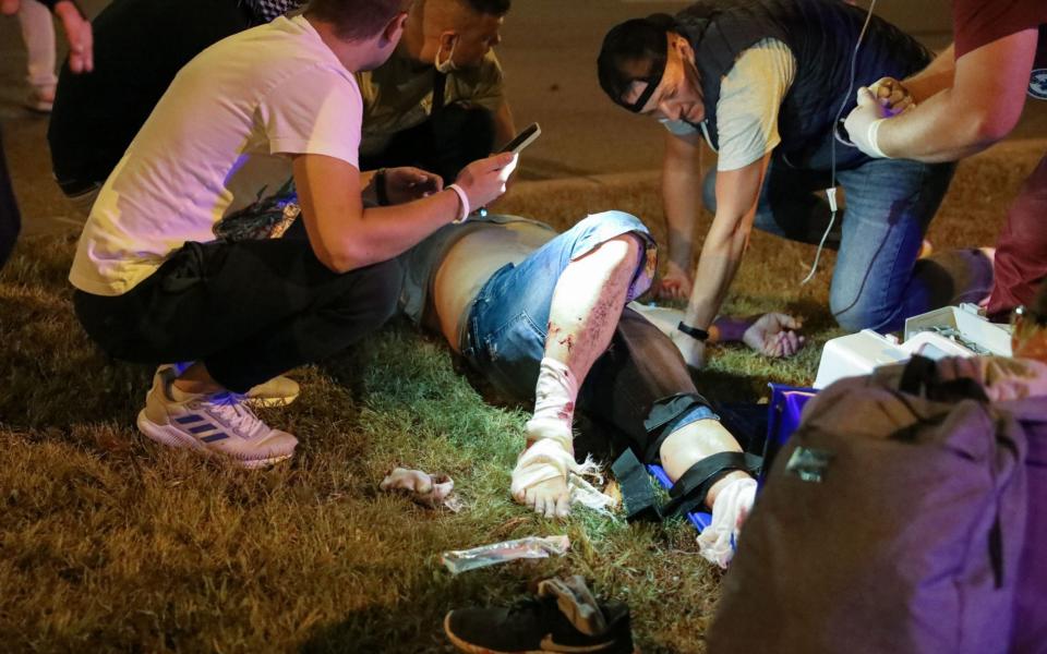 Demonstrators try to aid a man injured in bloody clashes with police after polls closed n Minsk  - Shutterstock/STRINGER/EPA-EFE/Shutterstock