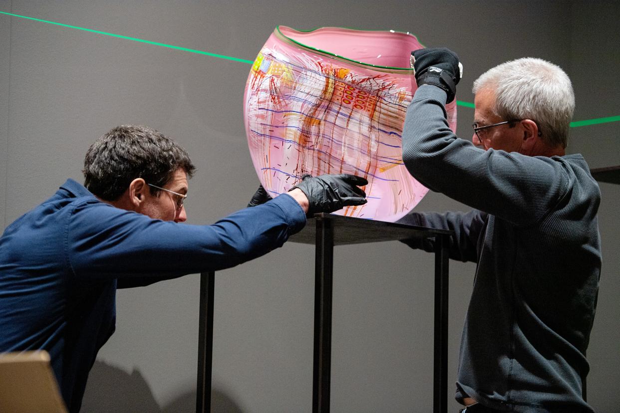 Chris Pfeifle, design builder, left, and Paul Arnhold, installer and lead packer, both with Chihuly Studio, install a piece for the Chihuly exhibition at the Biltmore Estate, March 20, 2024.