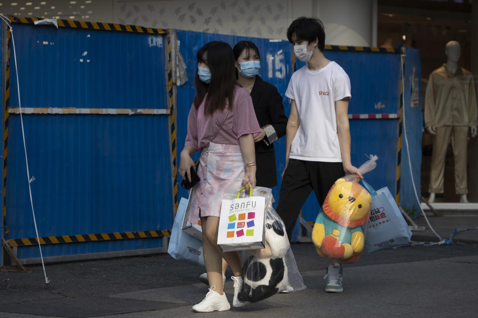 Residents carry their shopping at a retail street in Wuhan in central China's Hubei province on Thursday, April 9, 2020. Released from their apartments after a 2 1/2-month quarantine, residents of the city where the coronavirus pandemic began are cautiously returning to shopping and strolling in the street but say they still go out little and keep children home while they wait for schools to reopen. (AP Photo/Ng Han Guan)