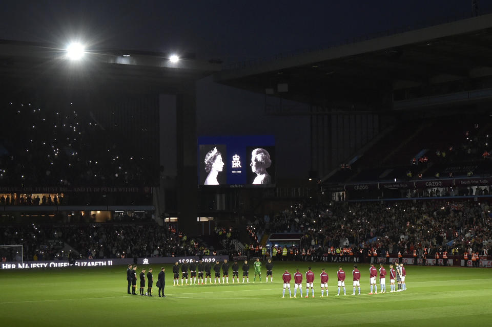 Players stand on the center of the pitch during a moment of silence tribute to Queen Elizabeth II before the English Premier League soccer match between Aston Villa and Southampton at Villa Park in Birmingham, England, Friday, Sept. 16, 2022. (AP Photo/Rui Vieira)