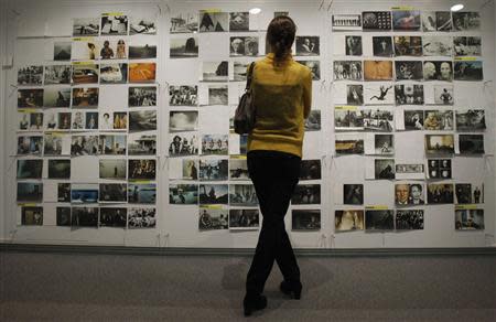 A visitor looks at a wall of pictures during a media preview ceremony before the opening of the exhibition of U.S. photographer Annie Leibovitz in Moscow October 11, 2011. REUTERS/Sergei Karpukhin
