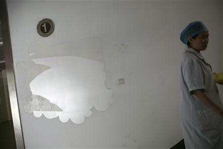 A medical staff walks past the remains of a Mead Johnson infant formula advertisement stuck on a wall at the corner of a staircase inside Hangzhou Tianmushan hospital, Zhejiang province, September 26, 2013. REUTERS/Chance Chan